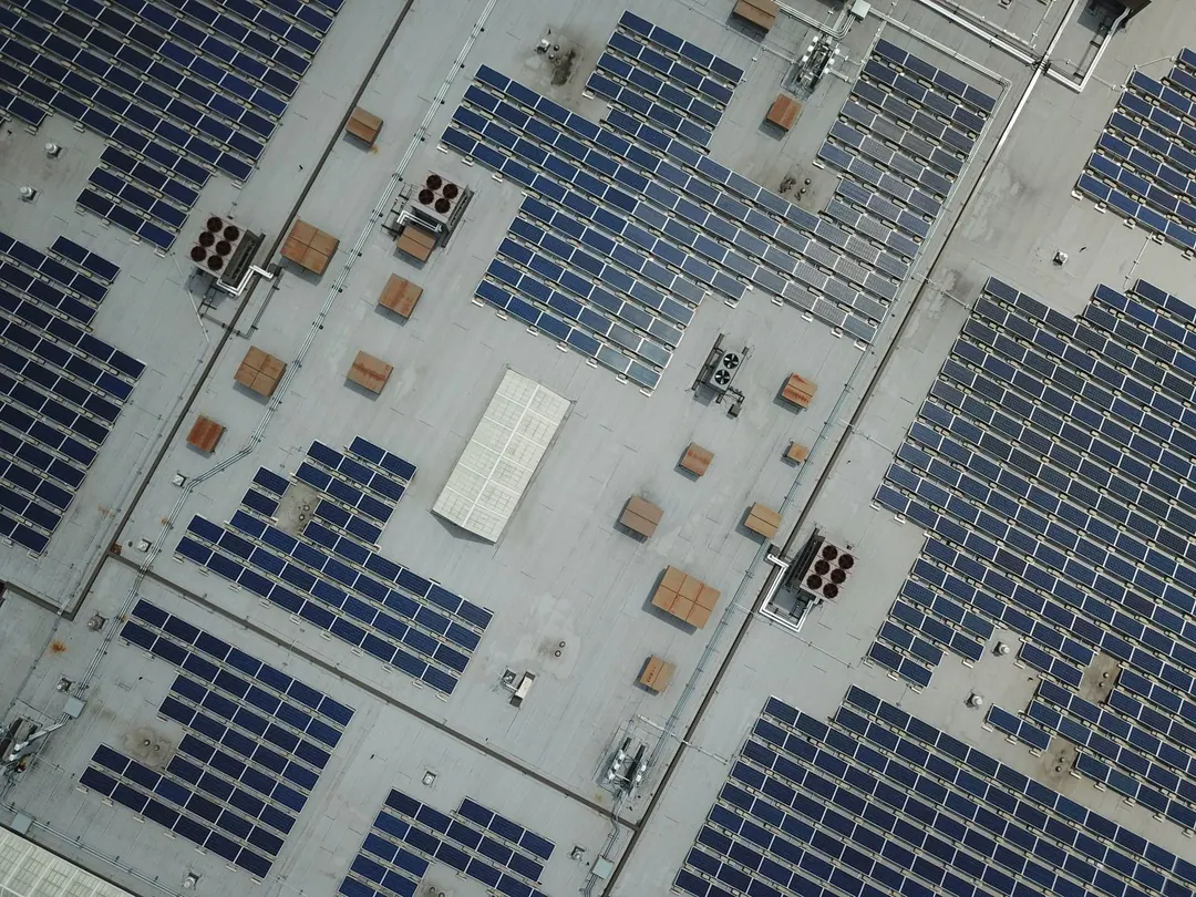 Rows of solar panels across a large flat industrial roof, seen from above