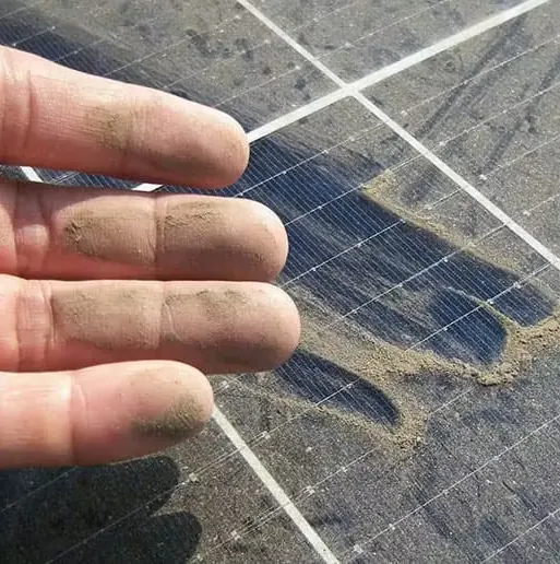 Dusty fingertips beside the clean streaks they wiped across a dirty solar panel